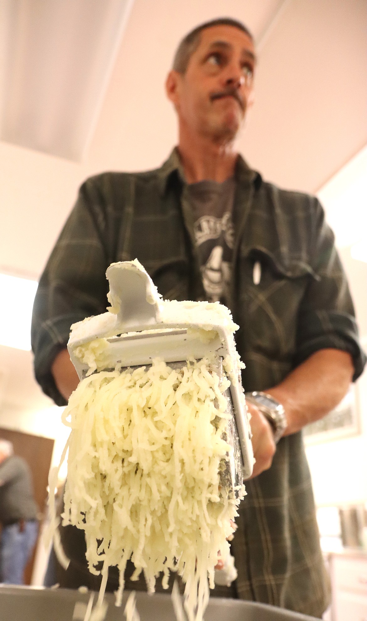 Eric Knutson runs potatoes for lefse through a hand grater on Wednesday.