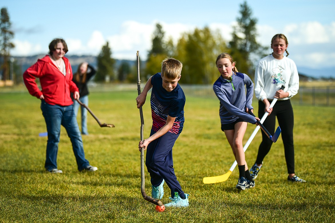 Liam Iverson and fellow classmates play a game of shinny, some using the root of a chokecherry tree, during Kila School's Native American Heritage Day in Kila on Friday, Sept. 29. (Casey Kreider/Daily Inter Lake)