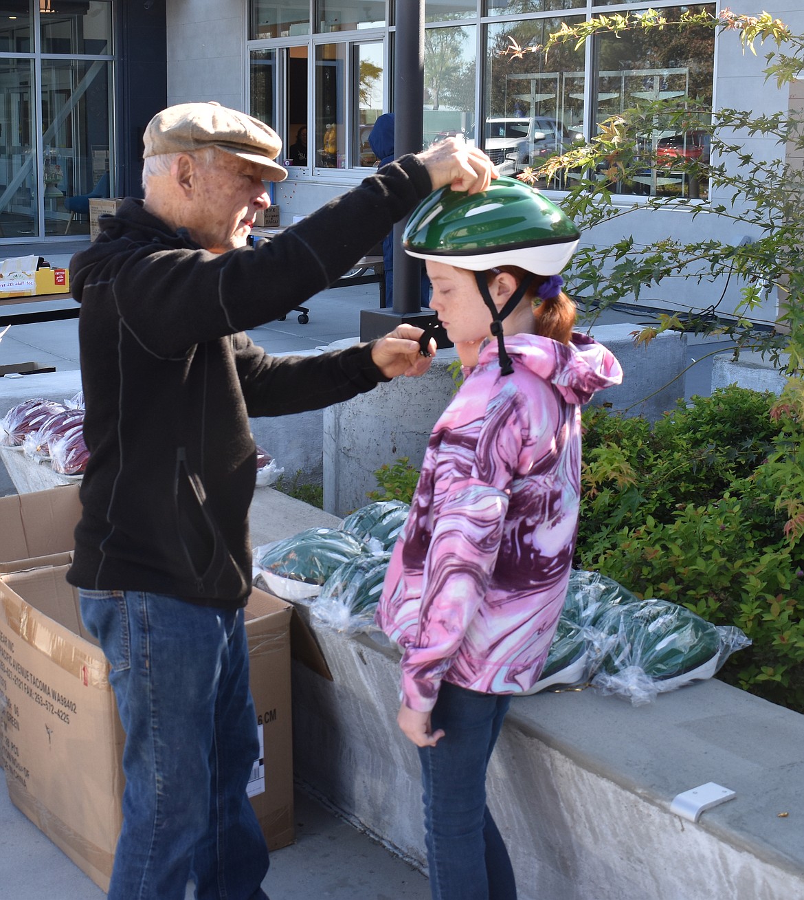 Richard Teals, a member of the Moses Lake Trail Planning Team and one of the organizers of the bike rodeo, fits Lydia Michie, 10, with a new bicycle helmet.