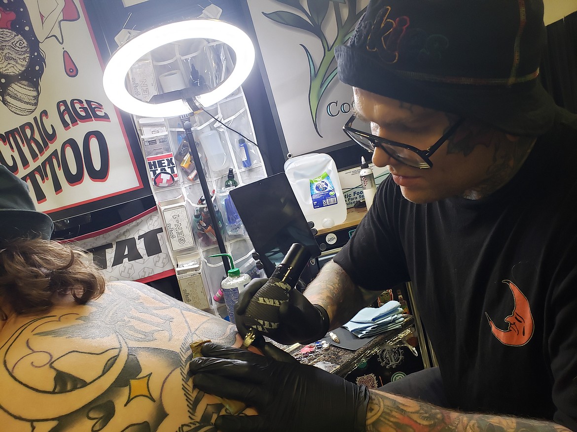 Artist Jake Sifford from Electric Age Tattoo in Coeur d'Alene tattoos a client during the Gem State Tattoo Convention on Sunday at the Kootenai County Fairgrounds.