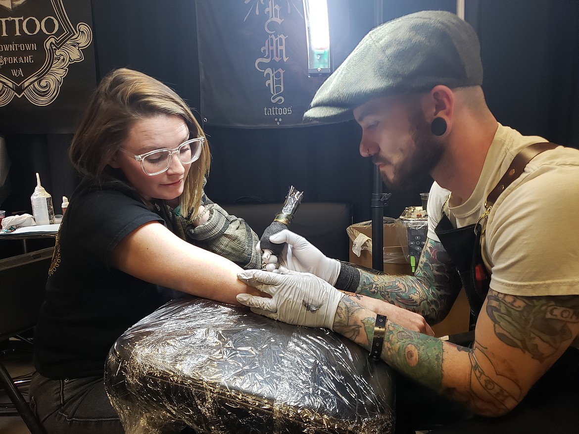 Tattoo Artist Kyle Carpino tattoos a bird onto Katrina Brisbin's arm Sunday at the Gem State Tattoo Convention.