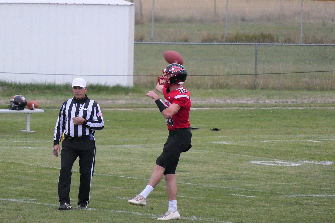 Hot Springs quarterback Nick McAllister looks downfield as he passes under the watchful eye of a referee during the Heat's win over White Sulphur Springs Friday night in Hot Springs. (Chuck Bandel/VP-MI)