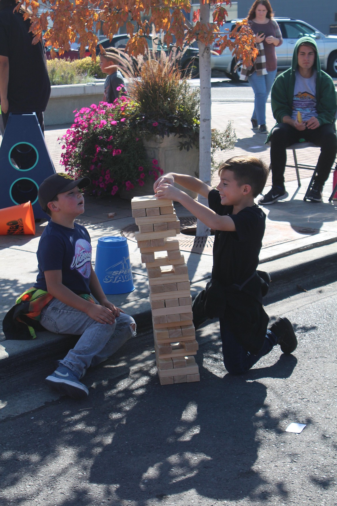 JJ Garza, left, and Uriah Santino, right, navigate the leaning tower of Jenga at the games provided by the city of Moses Lake’s mobile recreation van during the UMANI Festival.