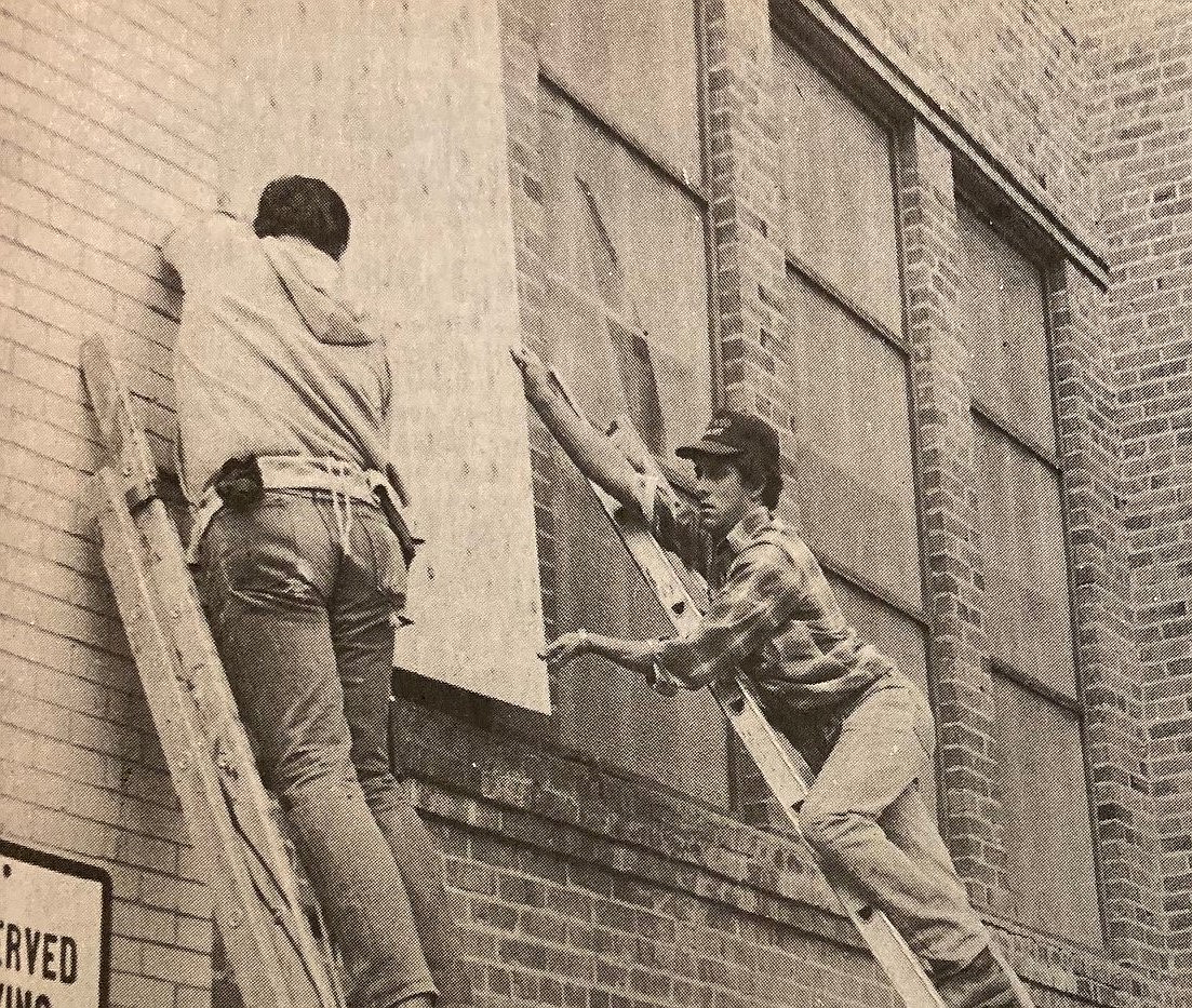 Two workers shutter the old Community Center.