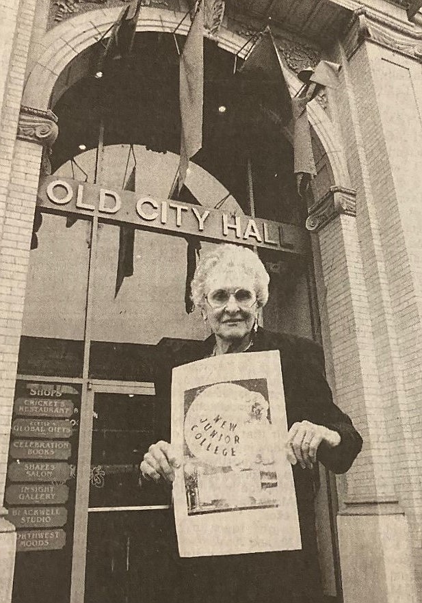 At the 60th anniversary of North Idaho College in 1993, Dorothy Earin Sonnichsen stands in front of Old City Hall, holding a 1933 ad for Coeur d'Alene Junior College.