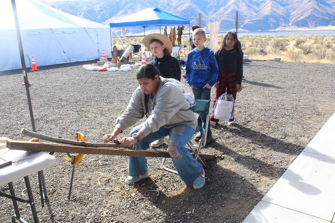 Children use a spokeshave to get the feel of making a canoe rib. Shawn Brigman, presenter at Archaeology Days, said the prehistoric builders would’ve found saplings and split them in half for the ribs.