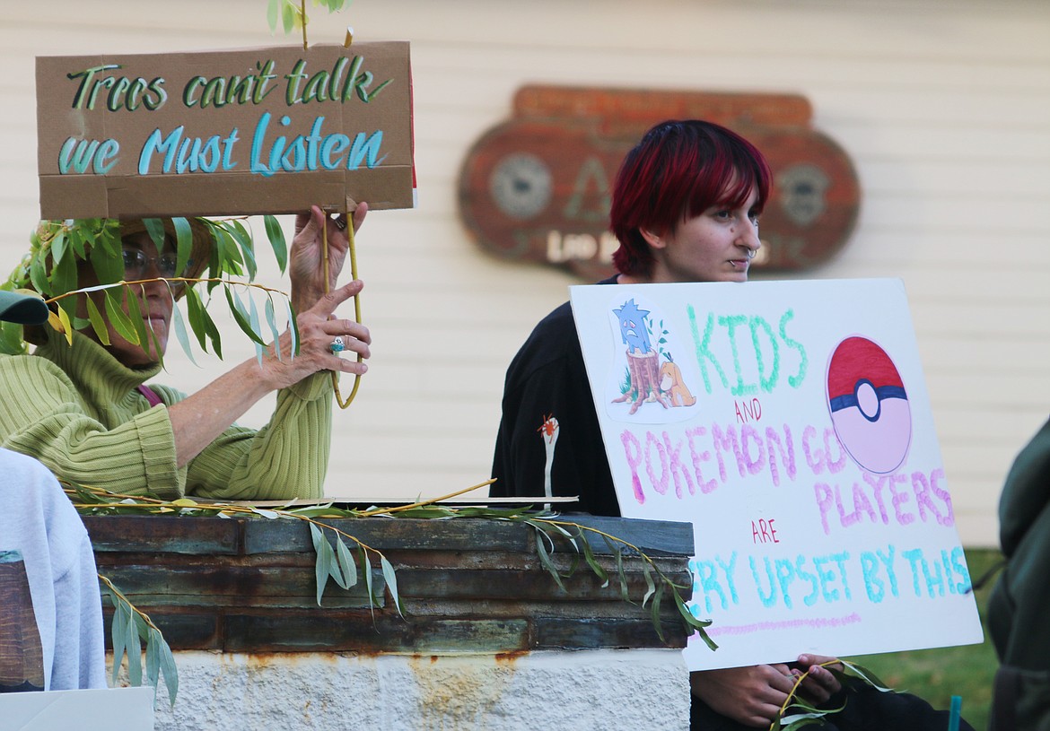 Gail Lyster, left, holds a sign calling on the city to change its mind and not cut down 20 trees at Travers Park. The trees are being removed to make way for construction of a new tennis and pickleball facility.