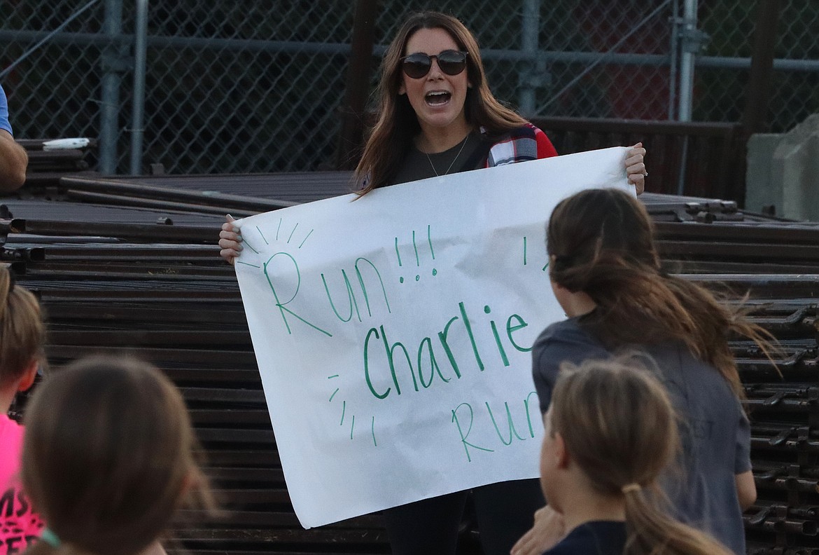 Katie Lind holds a poster and roots for her daughter in the Coeur d'Alene School District's annual elementary school cross country meet at the Kootenai County Fairgrounds on Thursday.