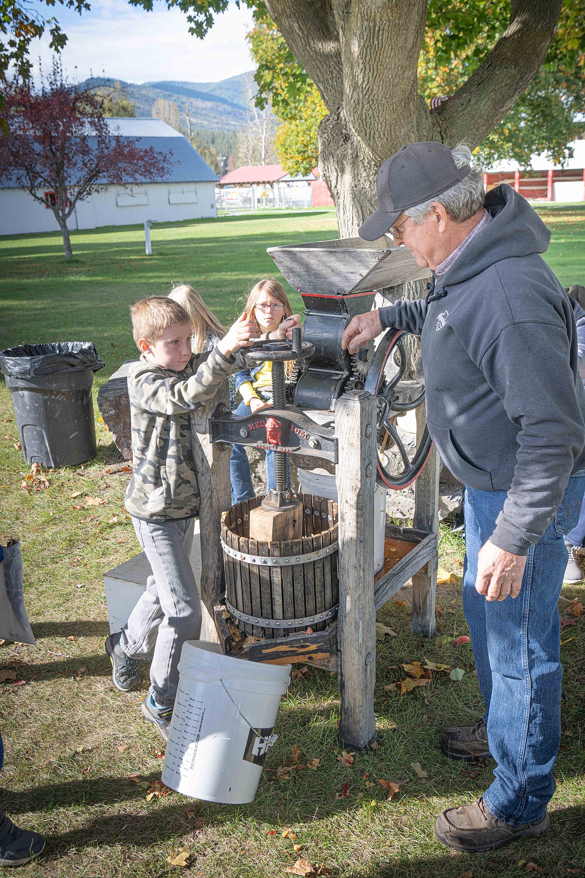 Bruce Beckstead shows Plains student Hoytt Miller how to make apple cider. (Tracy Scott/Valley Press)