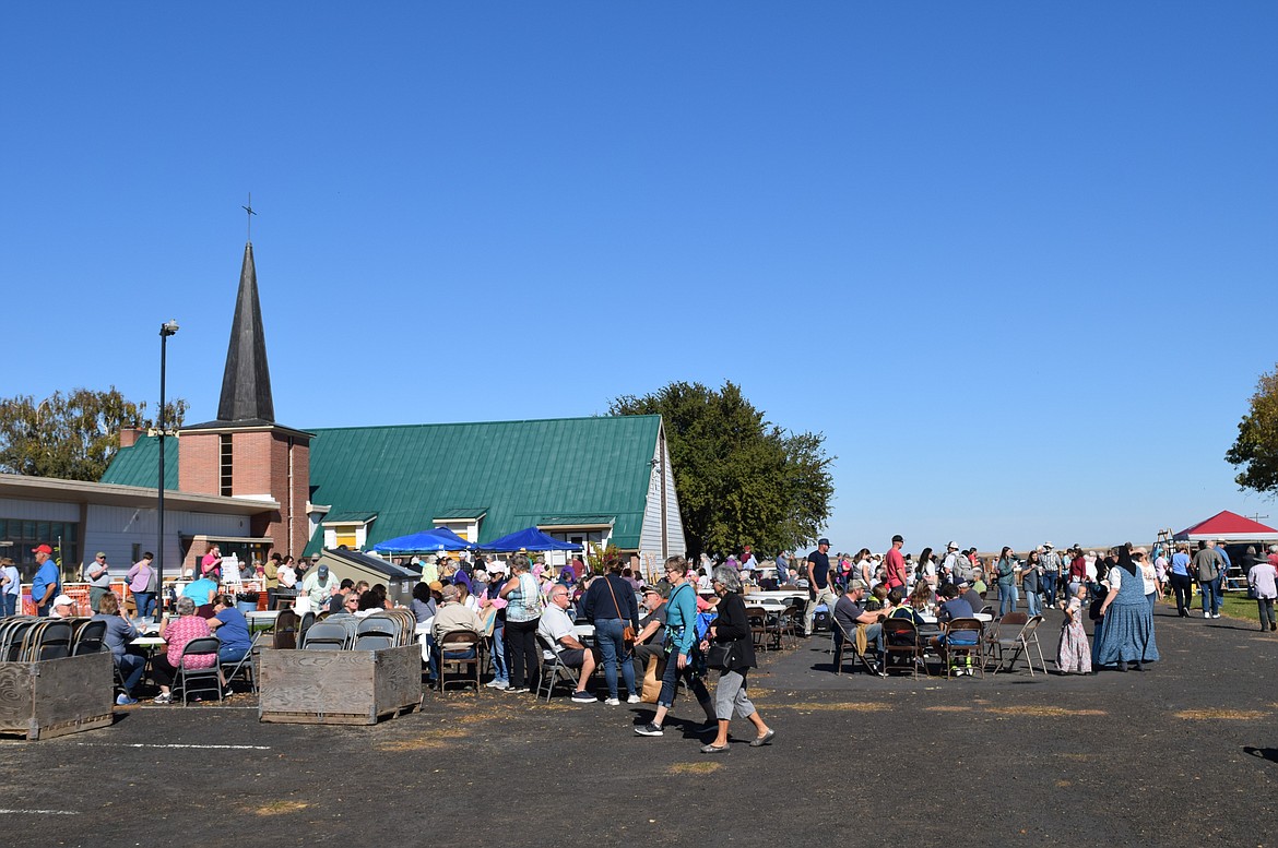 Members of the community enjoy food and sales booths outside of Menno Mennonite Church Saturday at the annual Mennonite Auction.