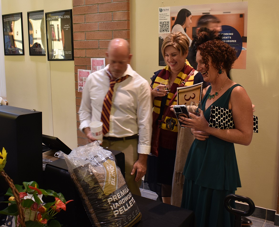 From left: Alan Clune, DeeDee Clune and Kristen Crawford check out silent auction items at the Boys & Girls Club’s auction Saturday.