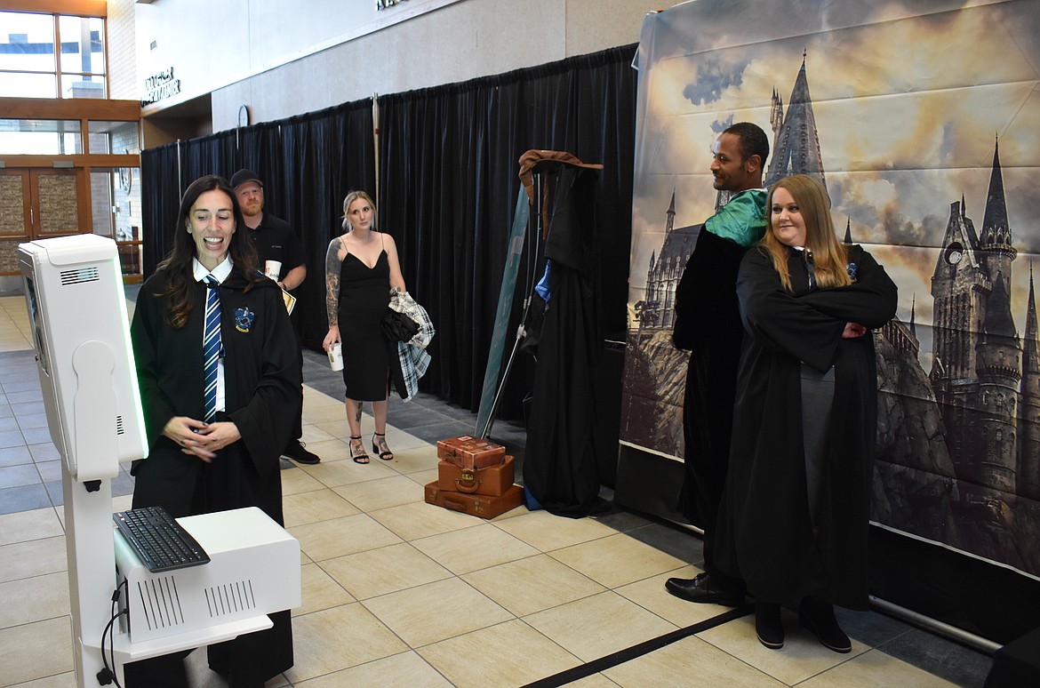 Tiffany Carvo, left, takes a photo of Duke Kilpatrick and Cassandra Adams against a magical backdrop at the Boys & Girls Club’s “A Night at Hogwarts” auction Saturday.