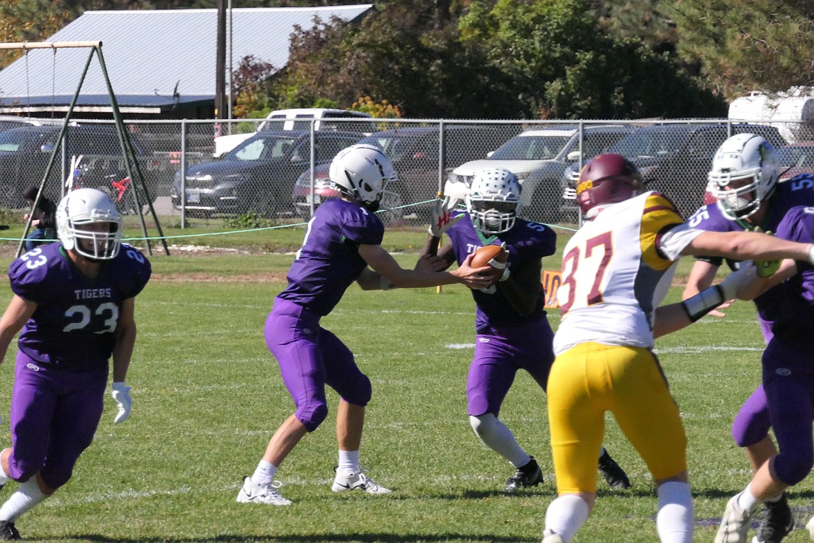 St. Regis-Mullan senior Kofi Appiah takes a handoff from quarterback Conner Lulis as #23 John Pruitt looks to block for him.  Appiah ran for 175 yards against Shelby during their game Saturday afternoon in St. Regis. (Chuck Bandel/MI-VP)