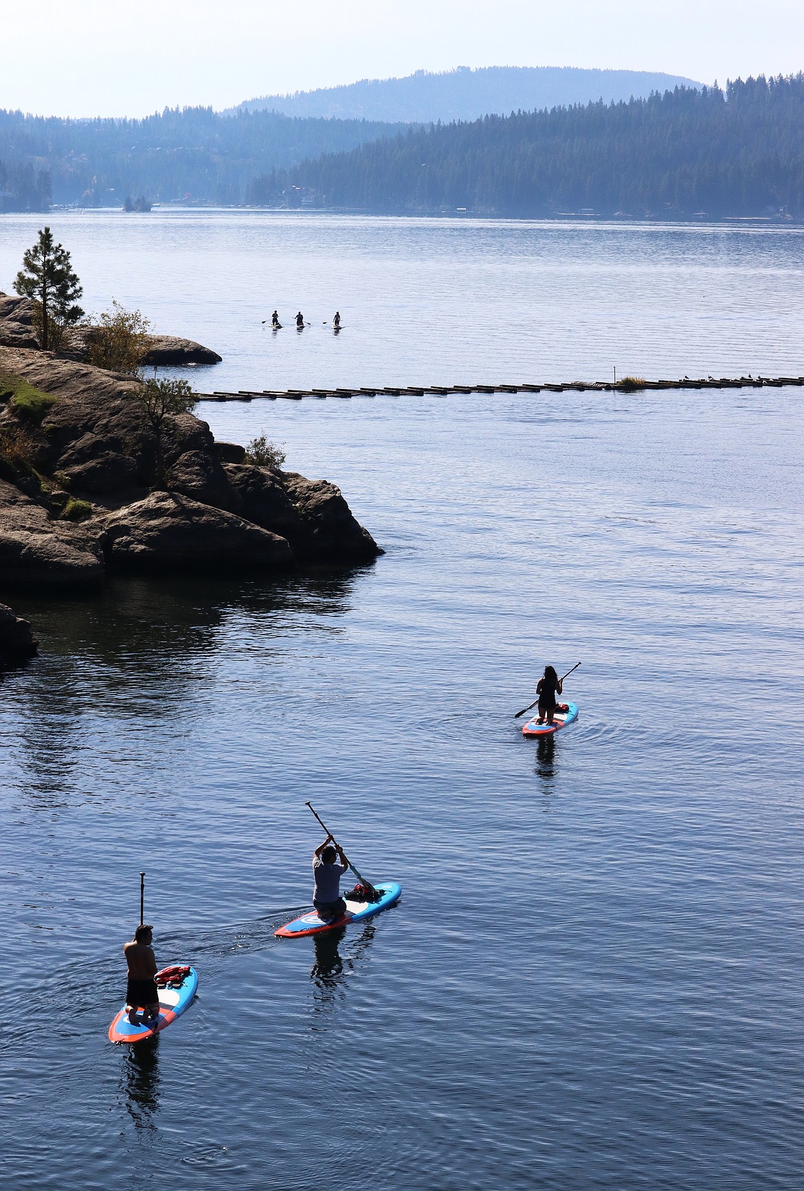 Three paddleboarders head out on Lake Coeur d'Alene while three make their back to shore Monday.