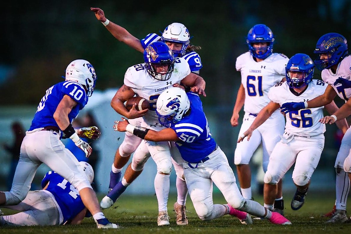 Libby running back Jace DeShazer (20) is brought down by Columbia Falls defenders Hunter Goodman (50) and Cody Schweikert (9) in the first quarter at Satterthwaite Field on Friday, Oct. 6. (Casey Kreider/Daily Inter Lake)