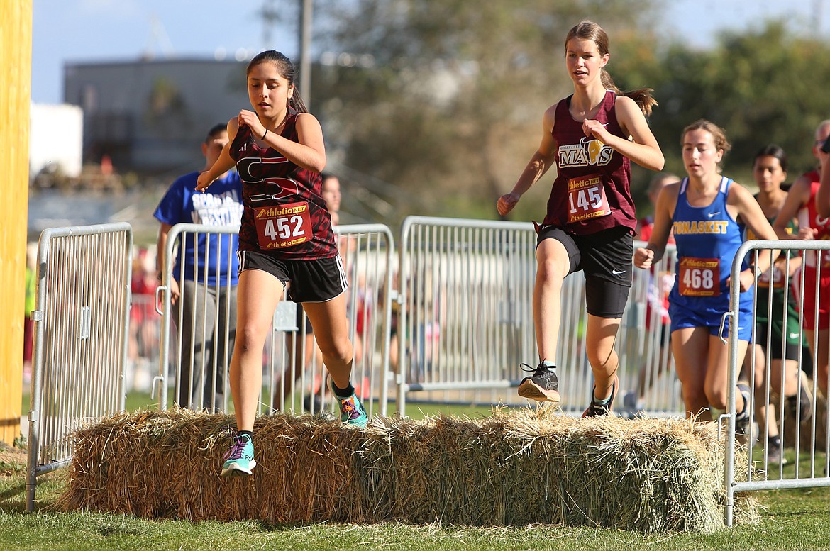 Runners leap over bales of hay at Thursday’s Moses Lake Cross Country Invitational at The Gorge Amphitheater.