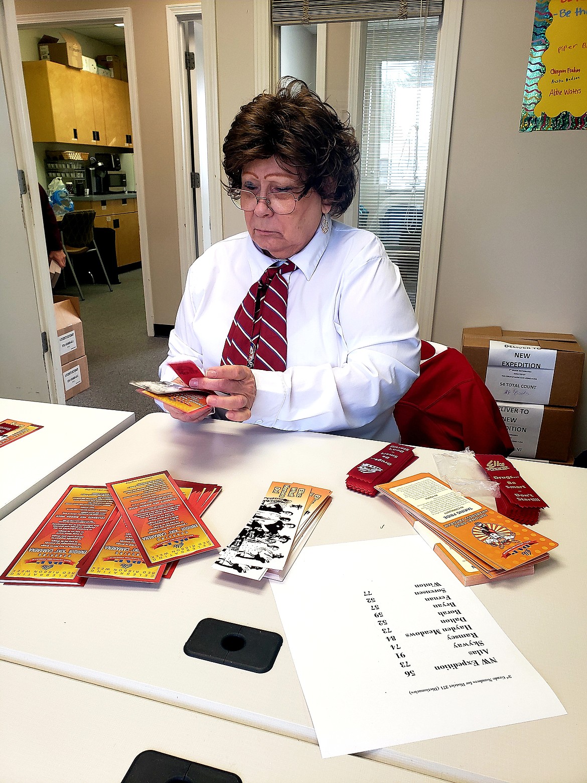 Elks Member Karen Magner groups books marks and red ribbons to stuff into  dictionaries. The dictionaries are delivered to third grade students across Kootenai County every year.