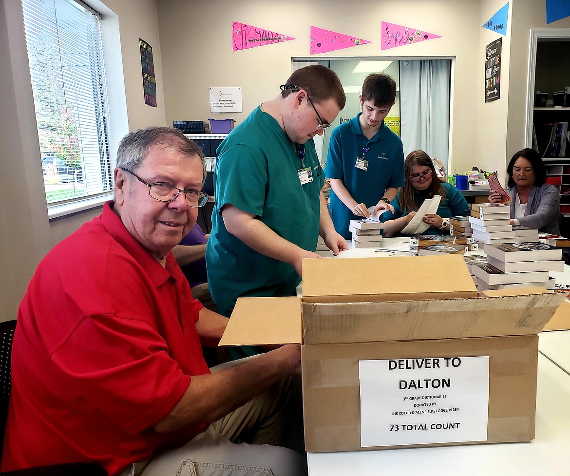 Elks Lodge member Patrick Braden stuffs dictionaries Monday with two bookmarks and a red ribbon before loading them into a box to be delivered to third grade students across Kootenai County.