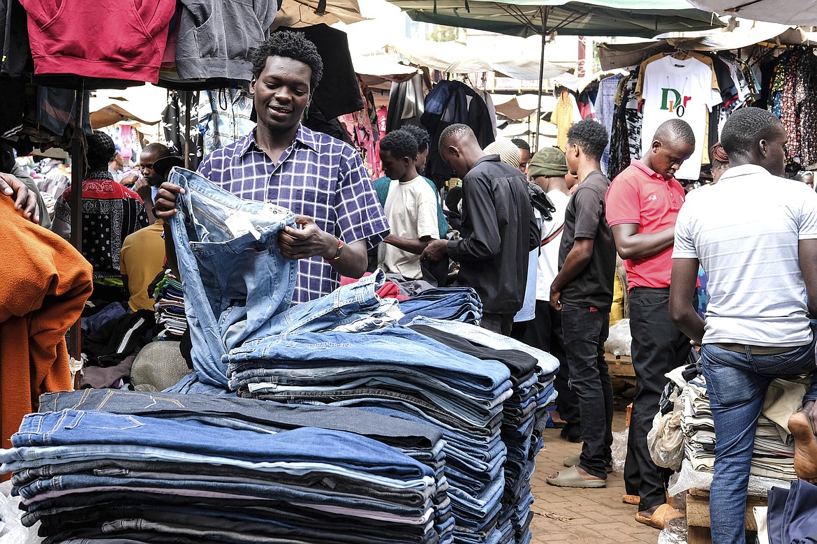 A second hand clothes retailer folds second hand jeans at his stall at Owino Market in Kampala, the capital of Uganda,Friday Sept. 15, 2023. Downtown Kampala’s Owino Market has long been a go-to enclave for rich and poor people alike looking for affordable but quality-made used clothes, underscoring perceptions that Western fashion is superior to what is made at home. But, despite their popularity, secondhand clothes are facing increasing pushback. (AP Photo/Hajarah Nalwadda)