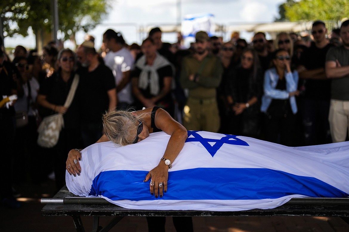 Antonio Macías' mother cries over her son's body covered with the Israeli flag at Pardes Haim cemetery in Kfar Saba, near Tel Aviv, Israel, Sunday, Oct. 15, 2023. Macias was killed by Hamas militants while attending a music festival in southern Israel earlier this month. The Israeli public is in a state of shock a week after Hamas militants launched an unprecedented attack on Israel, killing scores of Israelis in border communities and kidnapping roughly 150 civilians. As families grieve the dead and agonize over the missing, many also pledge allegiance to the war effort, falling in line behind a government vowing total war on the Gaza Strip. (AP Photo/Francisco Seco, File)