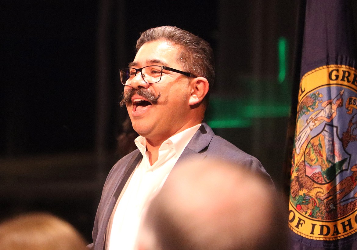Max Mendez leads the crowd in singing the national anthem Monday night at "Idaho Listens." Mendez asked the audience to look at each other, rather than the flag, as they sang.