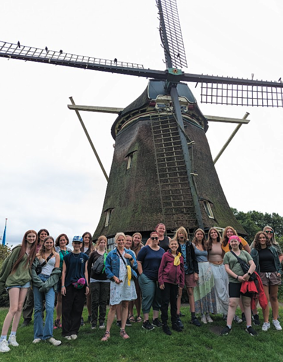 Student travelers and chaperones are seen near an iconic windmill in the Dutch countryside in August. Slots are open for students to travel abroad to Japan next spring with other trips coming up in the next couple years.