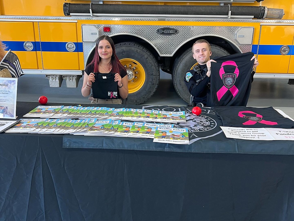 Representatives of the Othello Police Department hold up t-shirts for sale as part of a fundraiser for a local cancer group during the Adams County Fire District 5’s Oct. 12 open house.