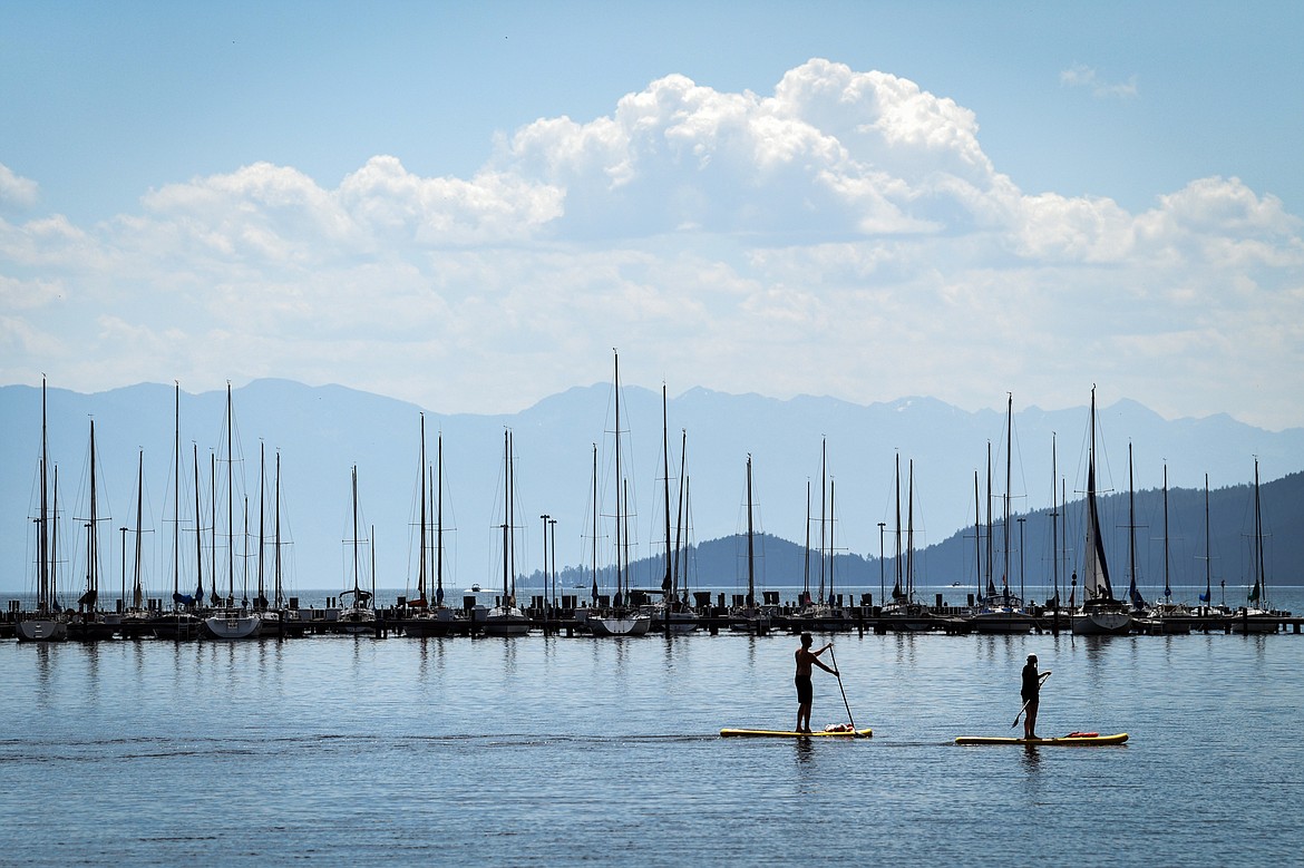 Paddleboarders float past boats docked at the North Flathead Yacht Club in Somers on Flathead Lake on Friday, June 30. (Casey Kreider/Daily Inter Lake)