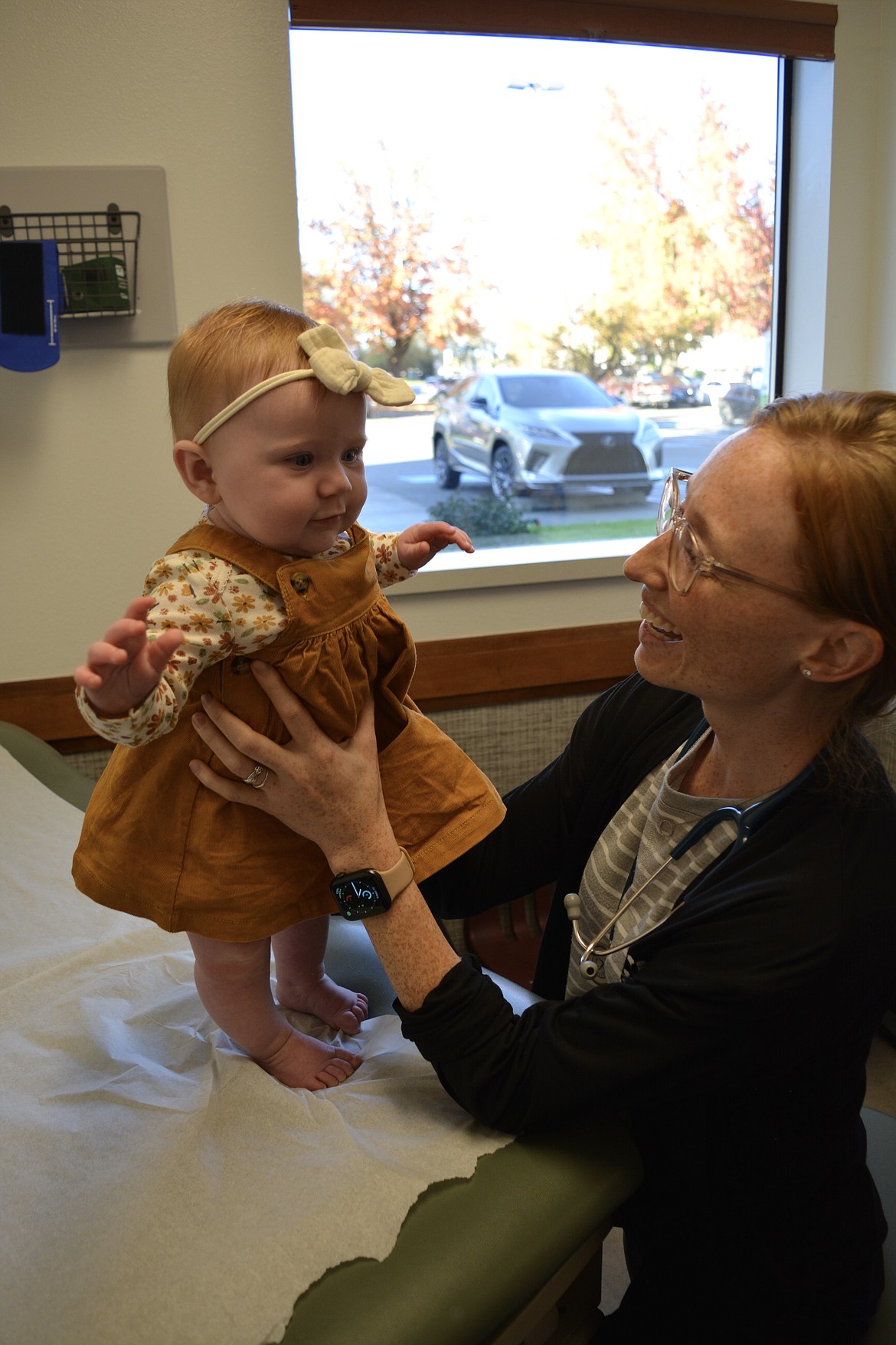 Dr. Nichole Buynak helps 6-month-old Harper Krantz stand on the patient table at Coeur d'Alene Pediatrics.