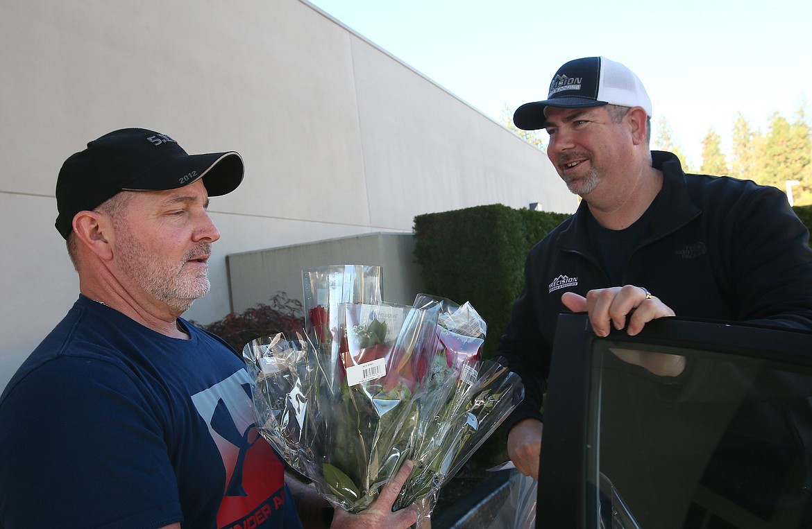 Coeur d'Alene Rotarian Steve Childers, left, hands off several roses to Tony Ball of Precision Gutters and Roofing during the Coeur d'Alene Rotary Rose Sale's annual distribution day Friday morning. More than 1,400 dozen roses were sold this year.