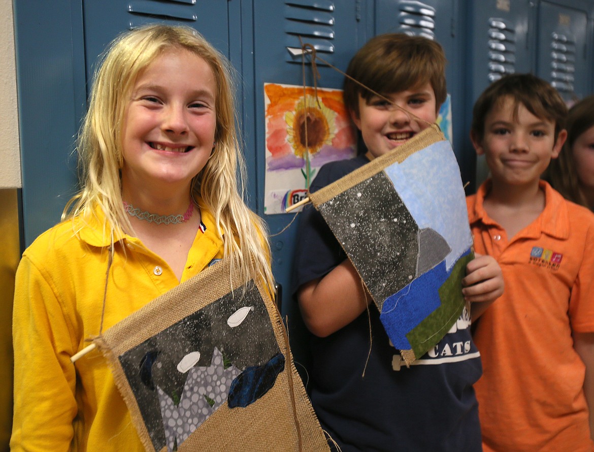 From left, fourth graders Sadie Brigham, Bridger Johnson and Fred Pigott show off their sewing masterpieces Friday at Sorensen Magnet School of the Arts and Humanities. For two weeks, students worked with an artist-in-residence to learning different sewing techniques.