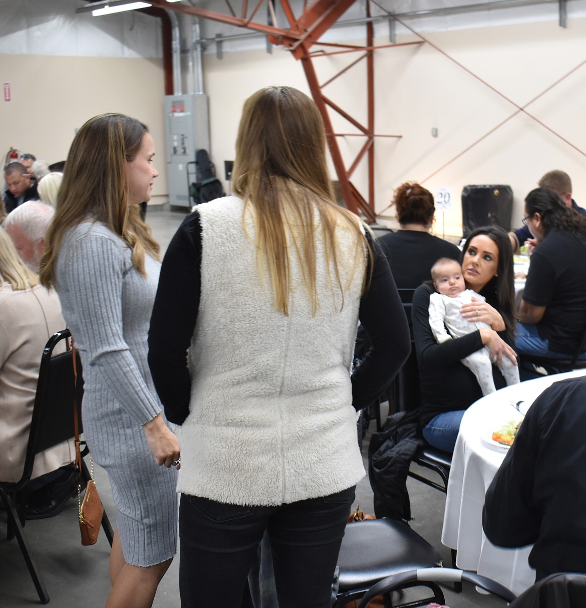 From left: Alona Trautman and Stephanie Cumaravel talk with Anna Smith, who’s holding Cumaravel’s  2-month-old daughter Willa, at the Crossroads banquet Saturday.