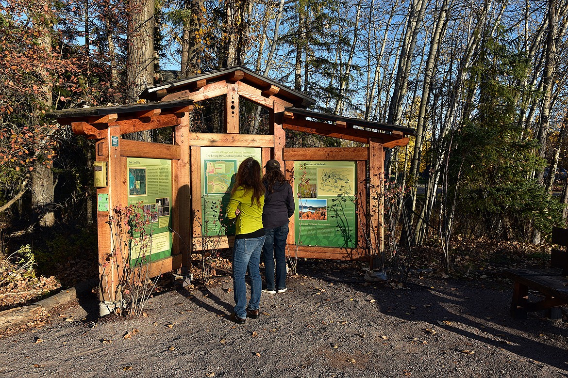 Two Montana Lake Conference participants check out the kiosk at the trailhead of the Viking Creek Trail. (Julie Engler/Whitefish Pilot)