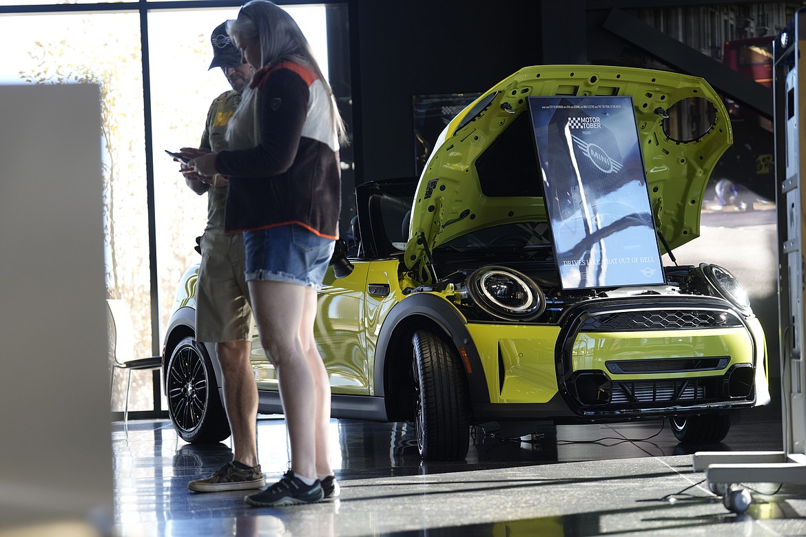 People talk near a 2024 Cooper S convertible on the floor of a Mini dealership Saturday, Oct. 21, 2023, in Highlands Ranch, Colo. On Friday, an inflation gauge that is closely monitored by the Federal Reserve showed price increases remained elevated in September amid brisk consumer spending and strong economic growth. (AP Photo/David Zalubowski)