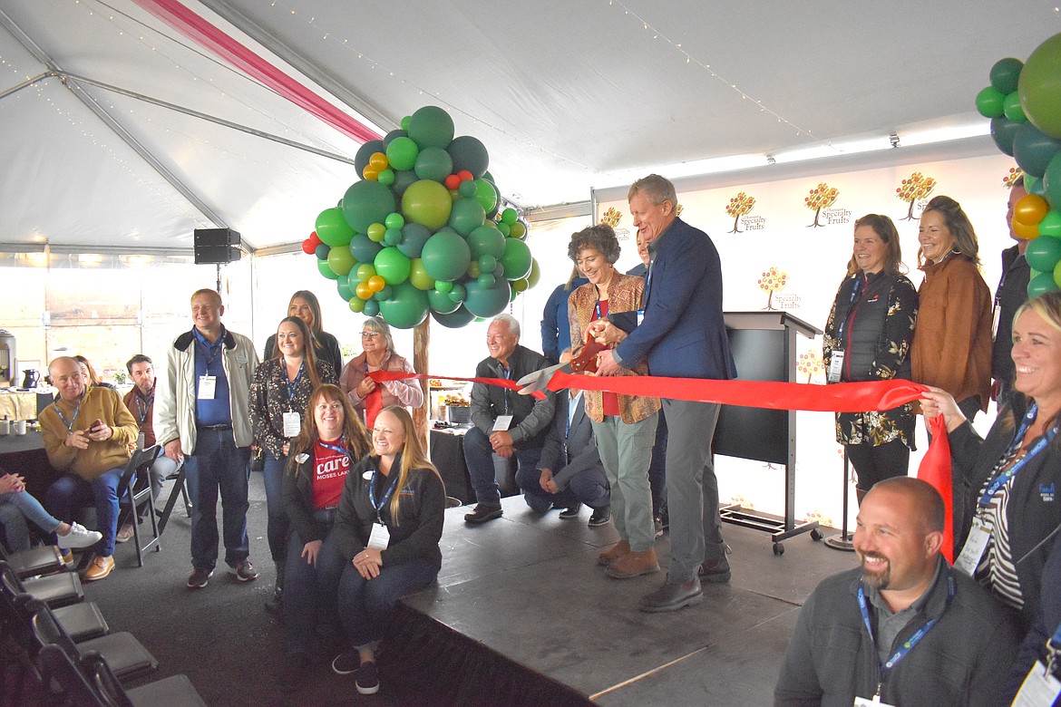 Okanagan Specialty Fruits founder and President Neal Carter, right, and his wife and co-founder Louisa Carter, cut the ribbon at the company’s new apple slicing and packing plant in Moses Lake.