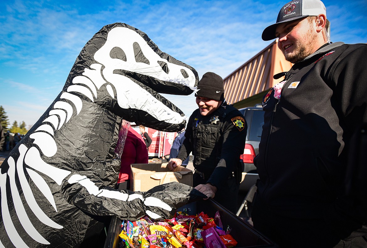 Dressed in a dinosaur skeleton suit, Jaxon Clarke receives a piece of candy at the trunk or treat event at the Boys and Girls Club of Glacier Country headquarters in Evergreen on Saturday, Oct. 28. The event was sponsored by the Flathead County Sheriff Posse, Evergreen Chamber of Commerce and local first responders. (Casey Kreider/Daily Inter Lake)