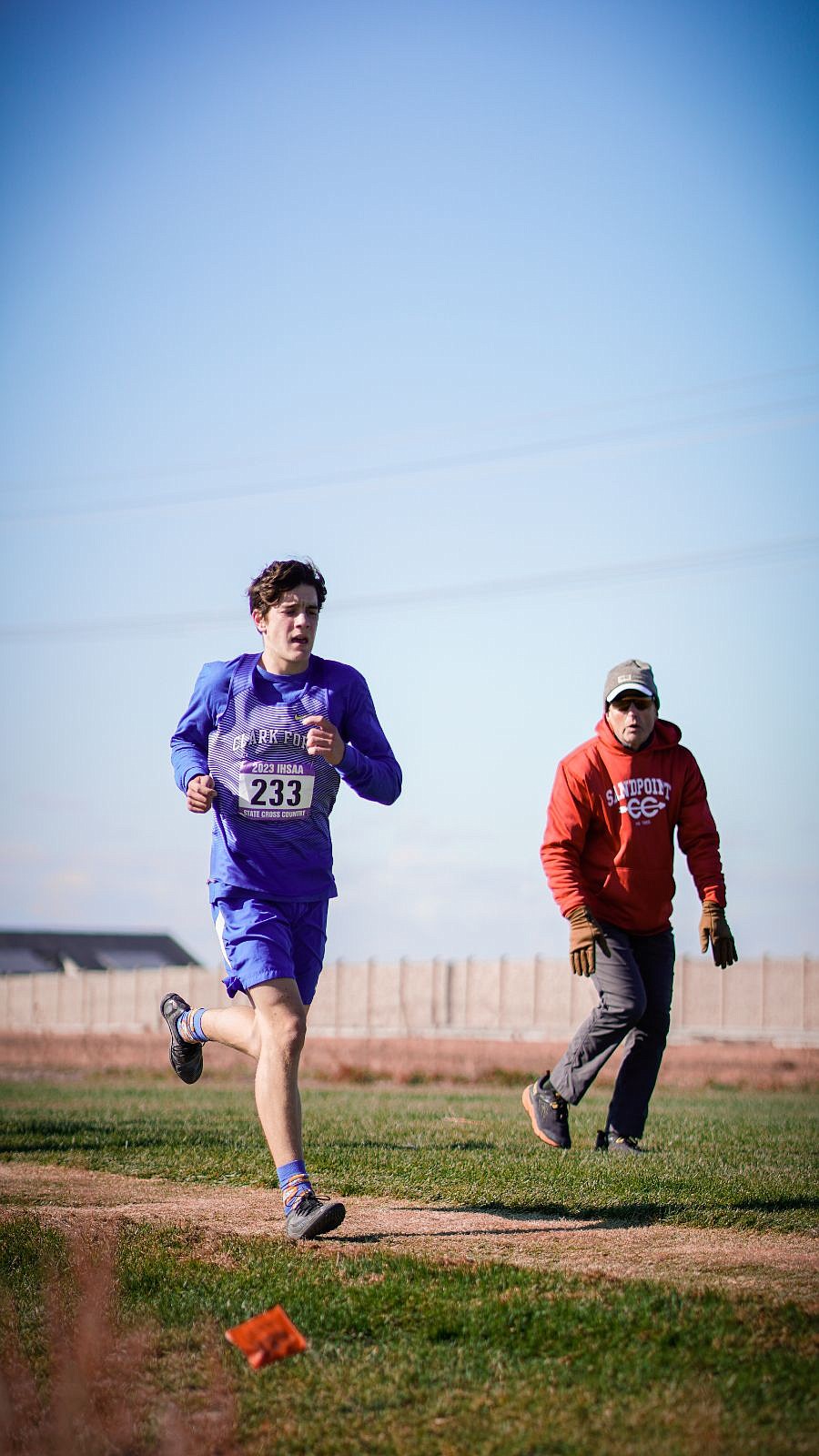 Clark Fork’s Westin Caven competes at the IHSAA State Cross Country Championships As he passes by, Sandpoint head coach Mike Ehredt yells words of encouragement.