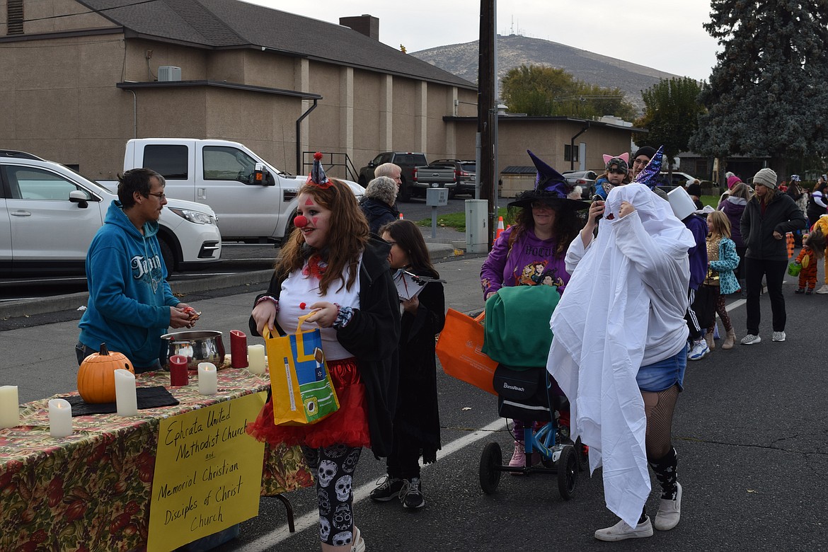 Clowns, ghosts and witches aplenty stepped out to grab hold of treats Tuesday night. Here, a clown, a couple of witches, and a specter visit the Ephrata United Methodist Church and Memorial Christian Disciples of Christ Church table which was bedecked with candles, a pumpkin and smiling volunteers.