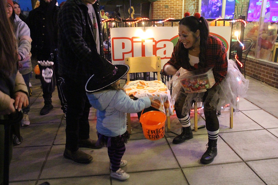 Harley Quin hands out candy to a witch with striped stockings and a lighted hat during the Downtown Trick or Treat Tuesday in Quincy.