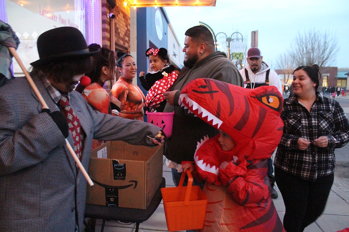 A dinosaur and a mini-Minnie collect some candy outside a Quincy business Tuesday during the Downtown Trick or Treat.