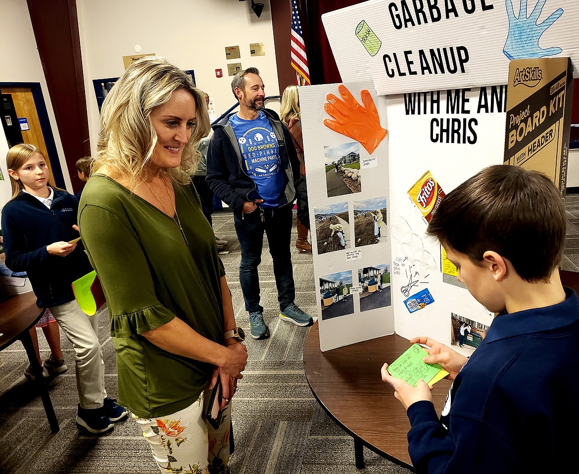 Coeur d'Alene Charter Academy language arts teacher Stacey Peppin listens to a student present his good deed board Wednesday. This was Peppin's fifth year participating in a school wide good deed project where sixth graders do good deeds in their community, then present them to parents.