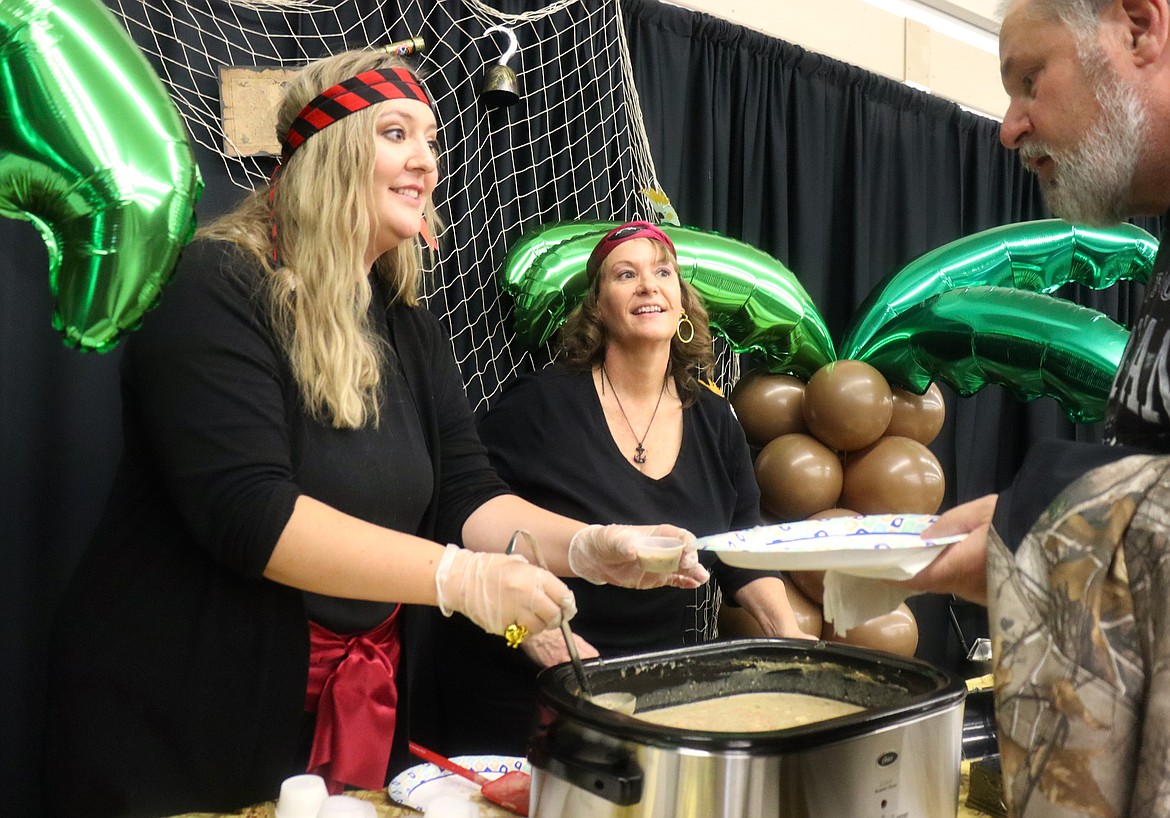 Catherine Monsey, left, and Kristy Golding with Advanced Benefits serve cups of "Pirates Cheesy Hamburger Gruel" at the "Souport The End of Homelessness" fundraiser for St. Vincent de Paul North Idaho at the Kootenai County Fairgrounds on Thursday.