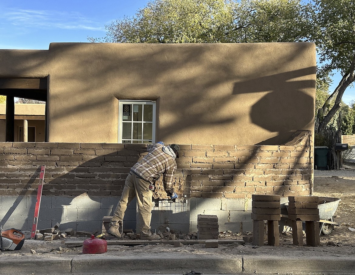 A mason works on an adobe-brick wall in on a residential lane lined with multimillion-dollar homes in Santa Fe, N.M., on Friday, Nov. 3, 2023. Voters are deciding whether to tax mansions to pay for affordable housing initiatives in a state capital city prized for its desert-mountain vistas, vibrant arts scene and stucco architecture rooted in Native American and Spanish-colonial tradition. (AP Photo/Morgan Lee)