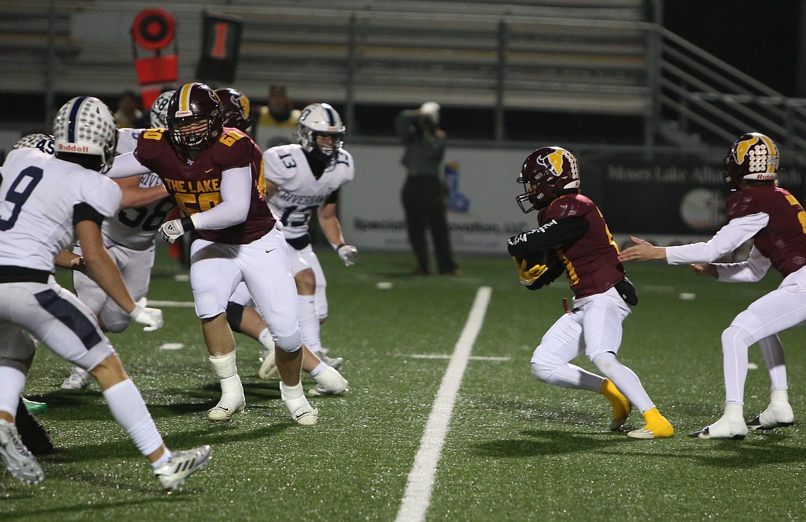 Moses Lake junior Brayden Kast (60) pulls to his left as junior Tommy Ranson Jr. carries the football.