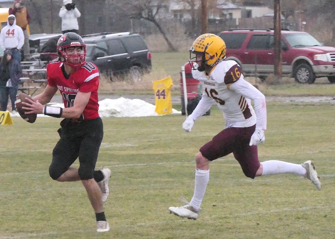 Hot Springs quarterback Nick McAllister eludes the rush from Harlowton-Ryegate's Angus Glennie during their quarterfinal playoff game Saturday afternoon in Hot Springs. (Chuck Bandel/VP-MI)