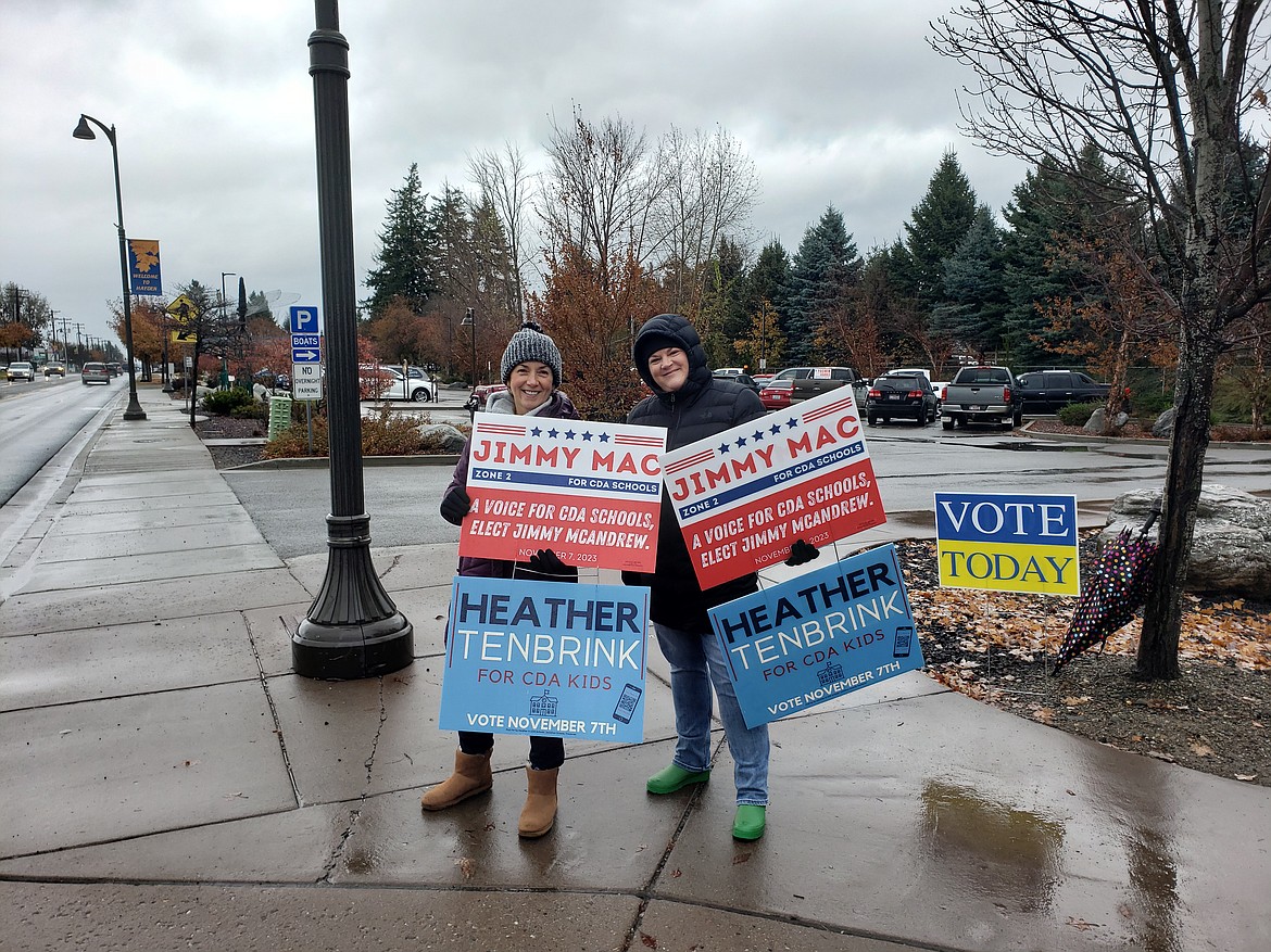 From left, volunteers Sara Meyer and Katie Morrisoe stand in the rain for hours from 7:30 a.m. to encourage people to vote Tuesday at the Hayden City Hall.