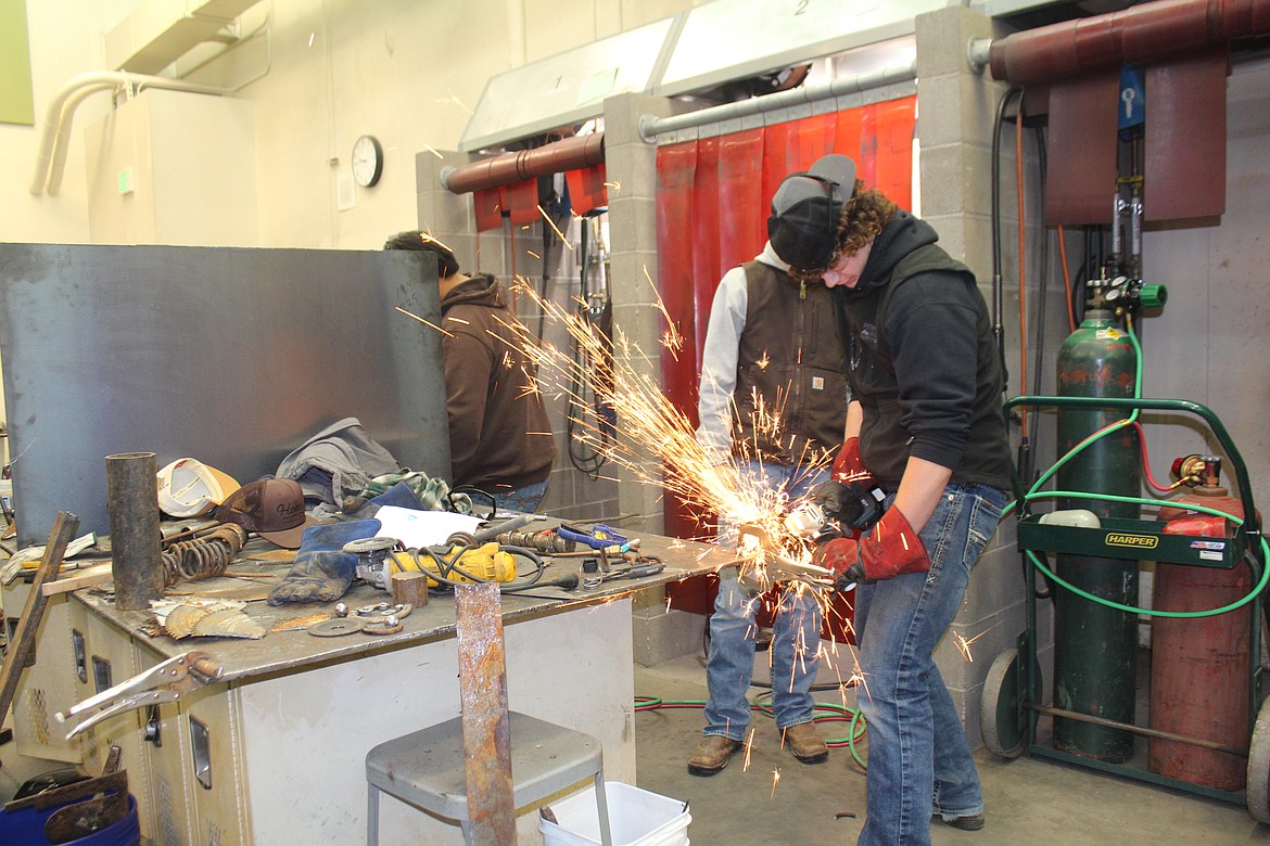 Kaine Geddes cuts apart metal springs that will become part of a fishing pole sculpture.