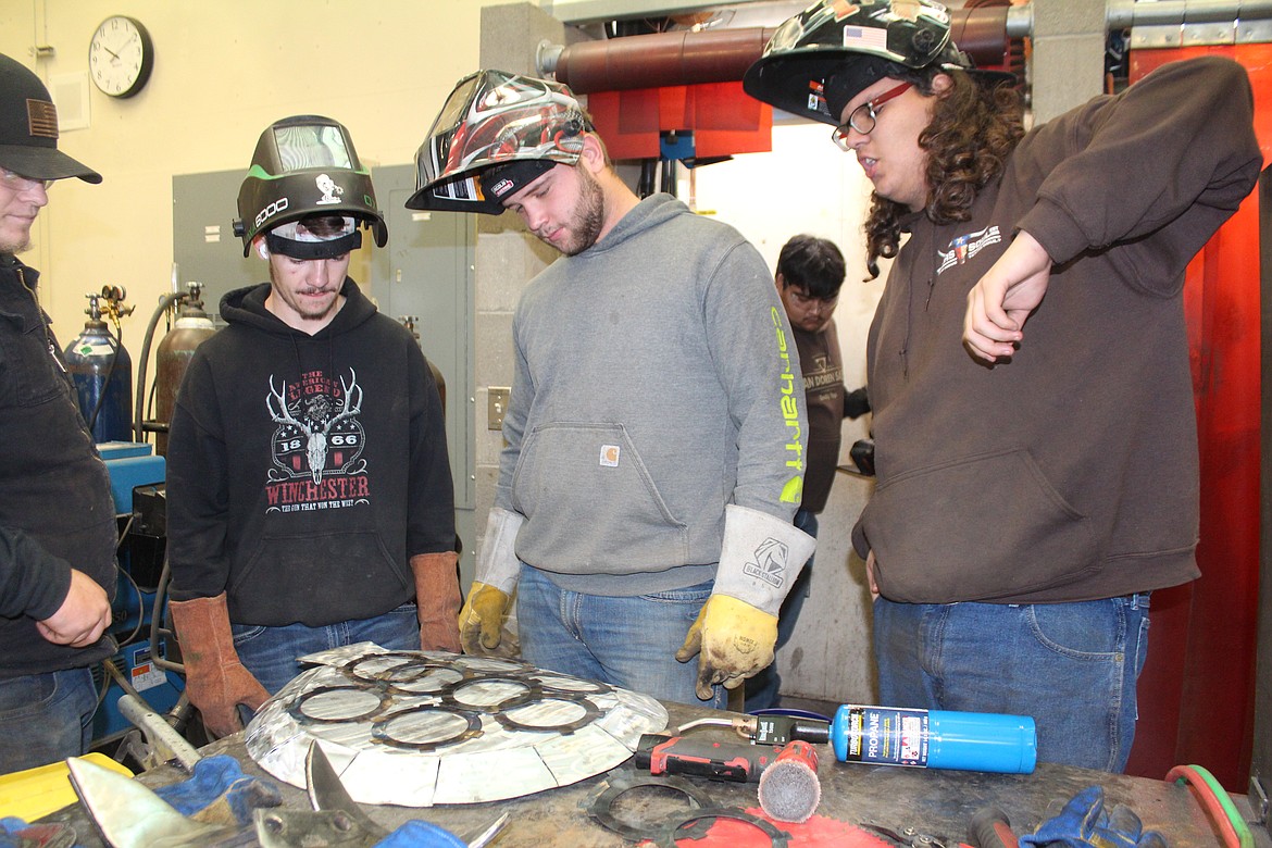 From left, Jesse Jamison, Jacob Anderson and Isiah Allen try to decide if they like the placement of elements in their scrap-metal work of art.