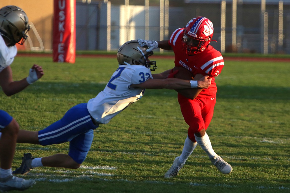 Othello senior Alex Mendez, in red, stiff-arms a Kelso defender.