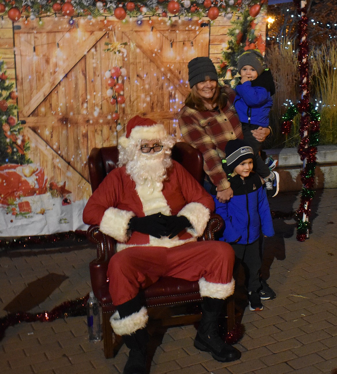 Kasee Smith and her grandsons Kaden Fitterer, 2, and Kyren Fitterer, 4, have their picture taken with Santa Claus, sometimes known as Wiley Farrer, at the tree lighting Friday in Sinkiuse Square in Moses Lake. Kyren admitted he’d asked Santa for a Mighty Pup.